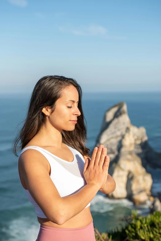 a woman standing in a yoga position with hands clasped up