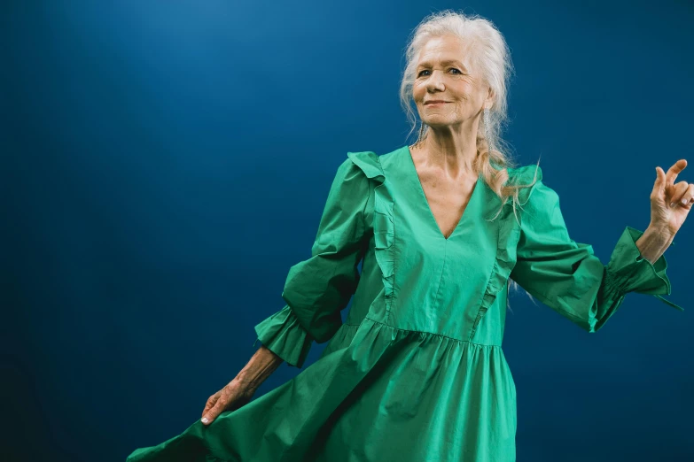 an older woman in green dress posing with her hands raised