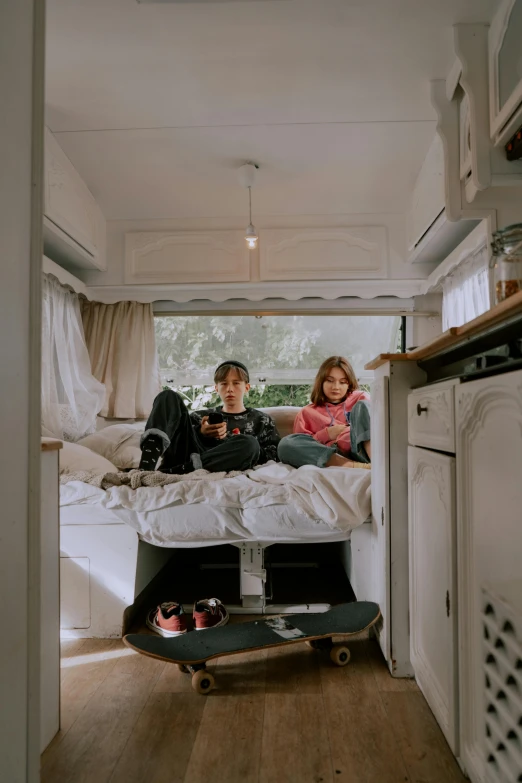 two people sitting on a bed in the inside of a camper