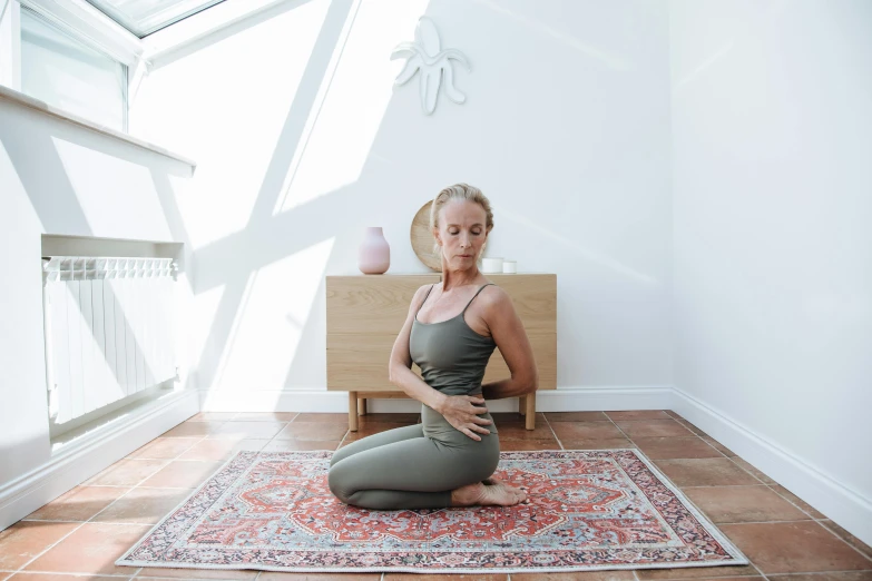 a woman in grey shirt sitting on top of rug