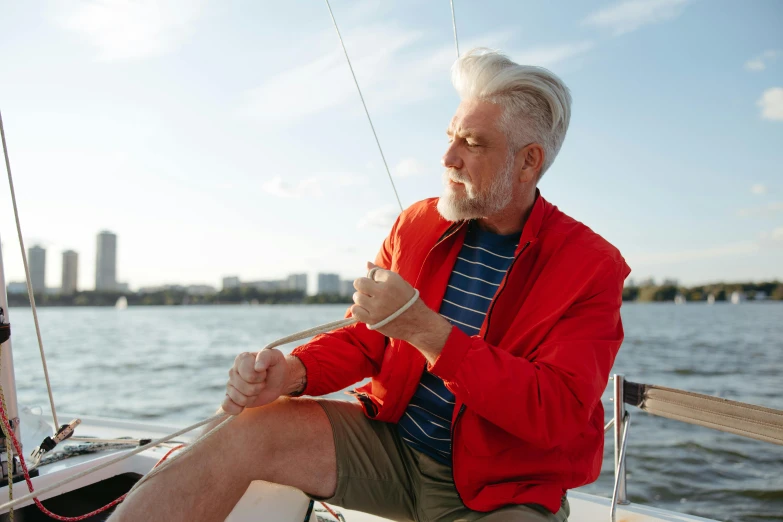 an old man is sitting at the front of a sail boat