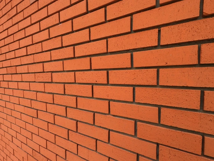 an orange brick wall on a street next to a parking meter