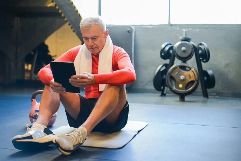 a man is sitting on a mat holding his tablet