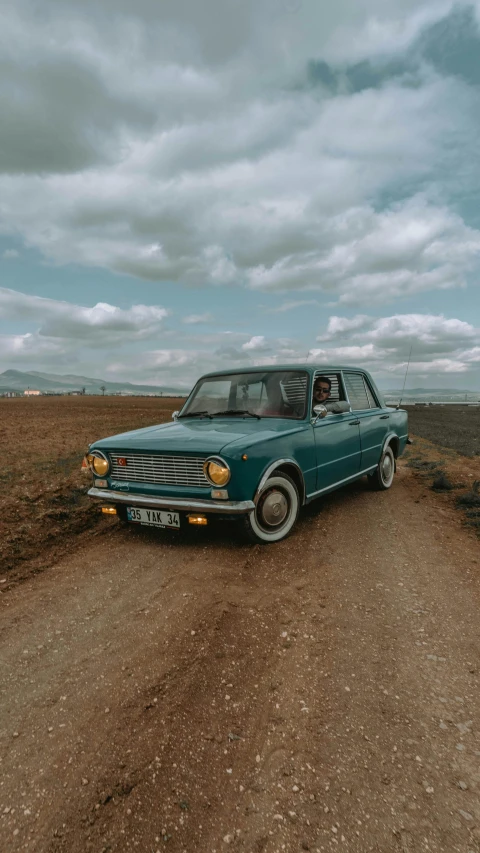 a car parked on a dirt road next to a field