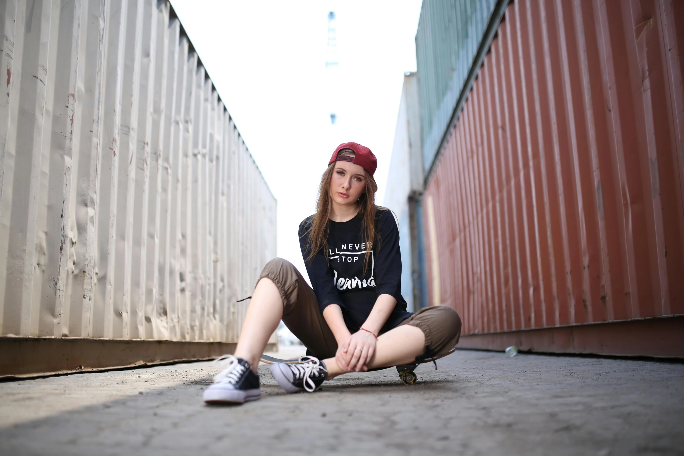 a woman sitting on a city sidewalk in a hat