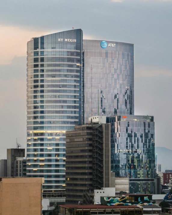 large buildings in the city with trees and clouds in the background