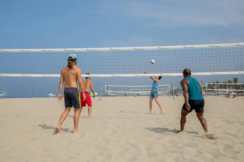 volley ball players and their backs are in the sand