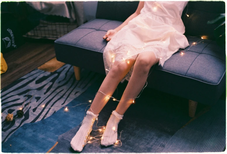 a woman in white dress sitting on a couch wearing socks and boots