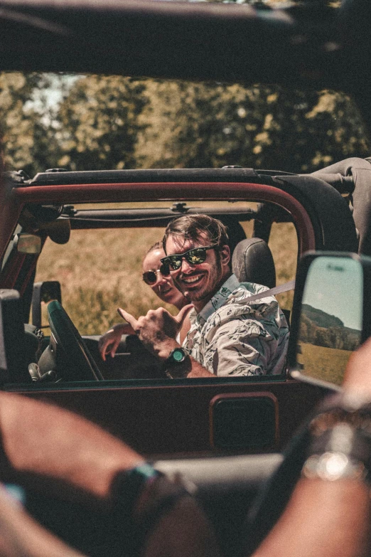 two people in a car smiling and posing for the camera