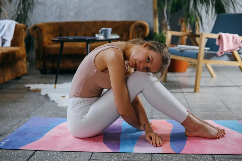 a woman is sitting on a pink mat in the middle of yoga