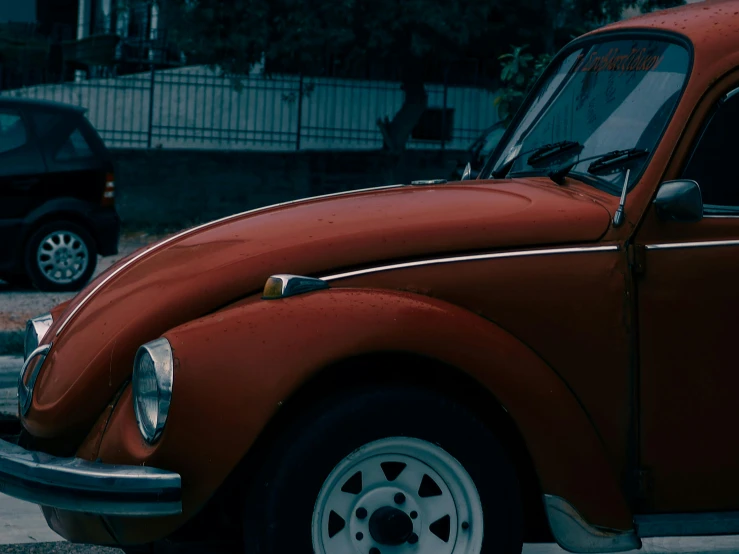 an old red car with its hood down sitting next to other cars