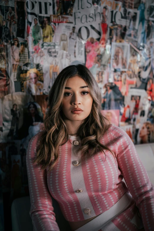 a woman sitting in front of wall with pictures