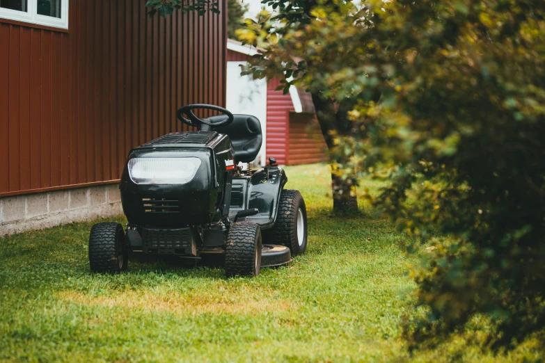 a lawn mower sitting on the grass outside a red house