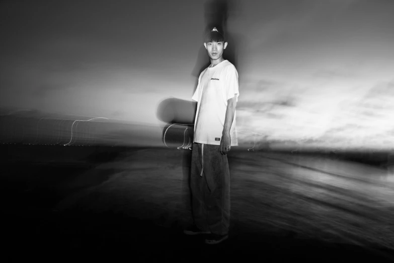 a man holding his skateboard with a black background