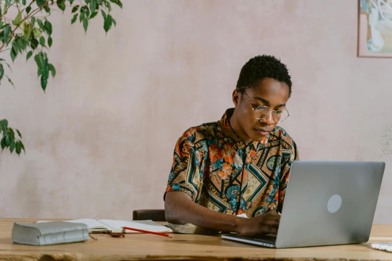 the man sitting in front of his computer is using his laptop