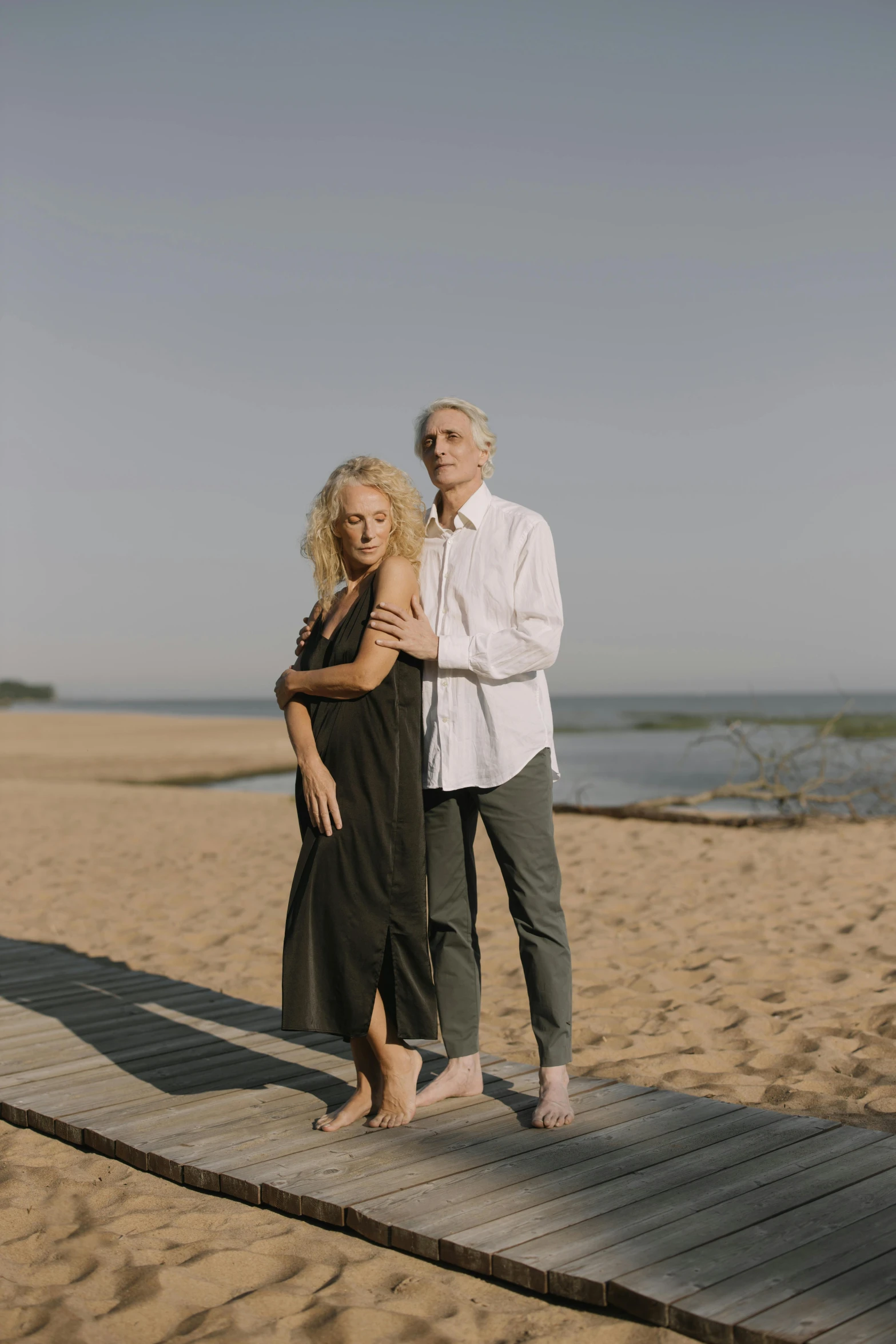 an elderly couple on the beach posing for their engagement picture