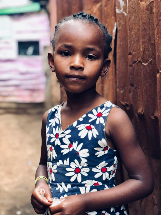 an african american girl with ids stands in front of a wall