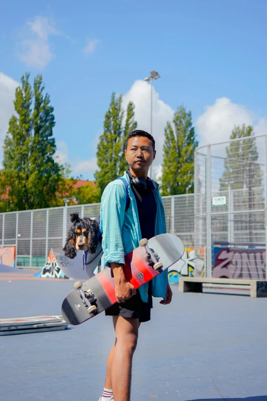 man in shorts with his dog wearing an iron helmet and holding a skateboard