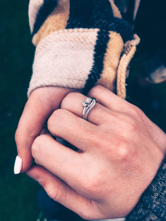 woman's hand holding engagement ring with diamond accents