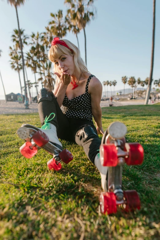 a woman sitting in the grass with her skateboards