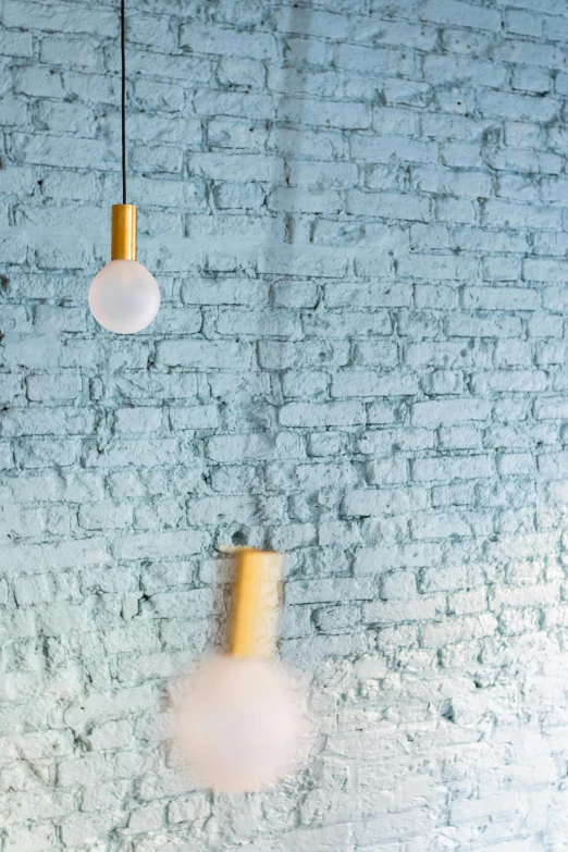 two lights and a pendant light are hanging from a brick wall