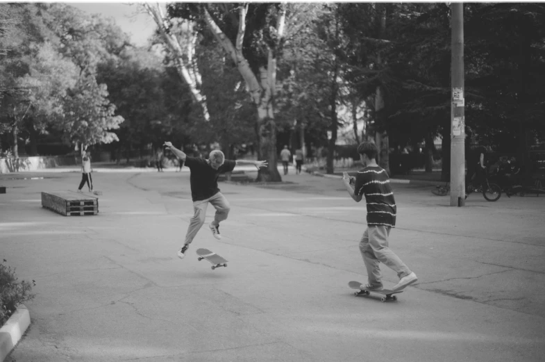 two guys on skateboards one doing tricks while the other is riding