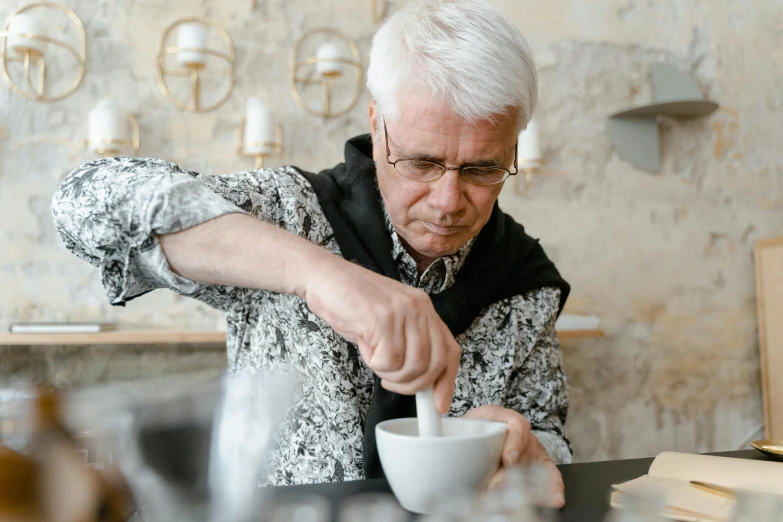 a man sitting at a table pouring a bowl of food