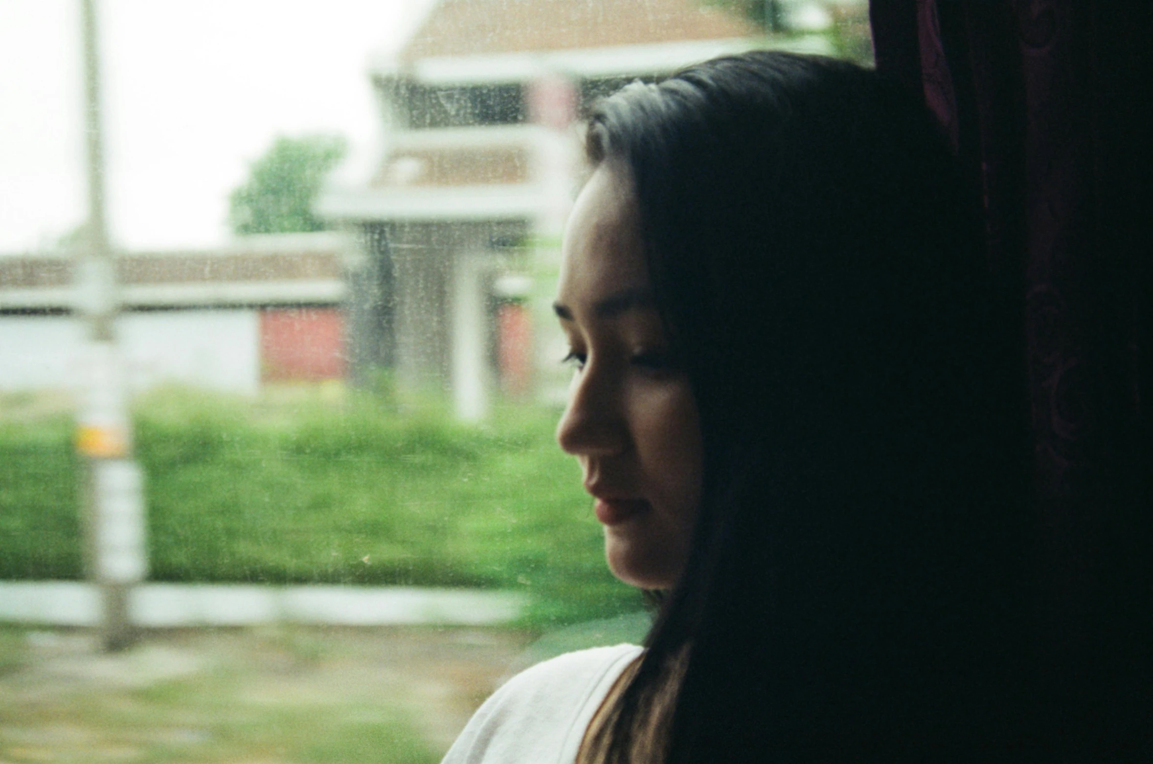 a girl looks out the window on an overcast day