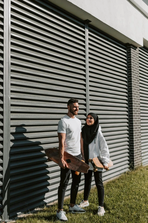two people pose outside next to a wall
