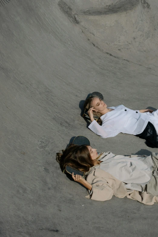 two girls laying down on the ground in the sand