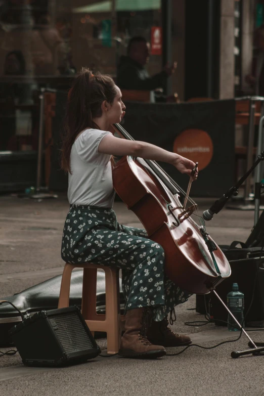 the woman sits on a chair playing the cello