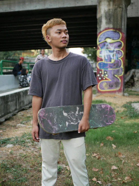 the man is holding his skateboard outside near some graffiti