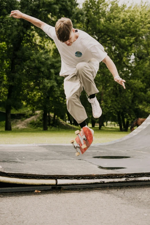 a  with long hair, wearing orange shoes and jumping on a skateboard