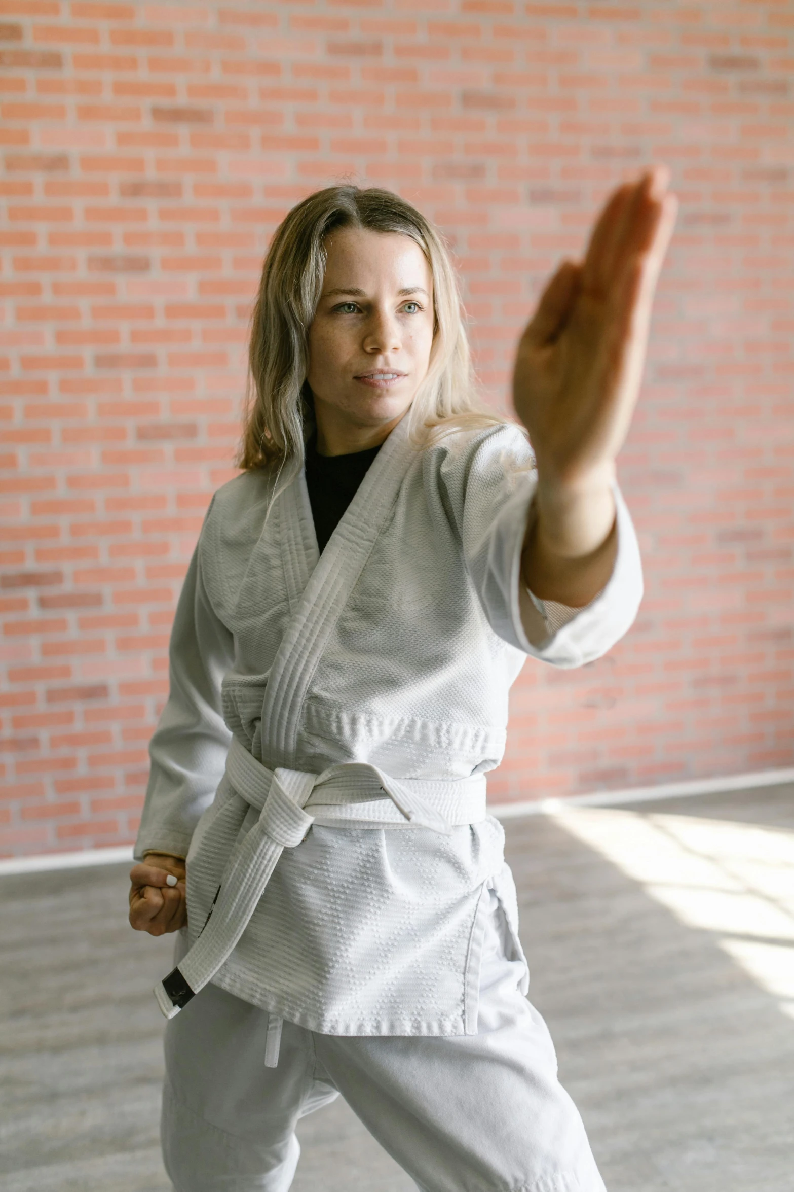 woman practicing a karate kick with brick wall