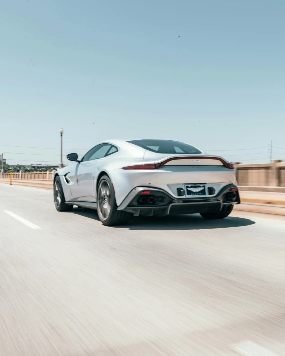 the rear end of a white sports car driving down the road