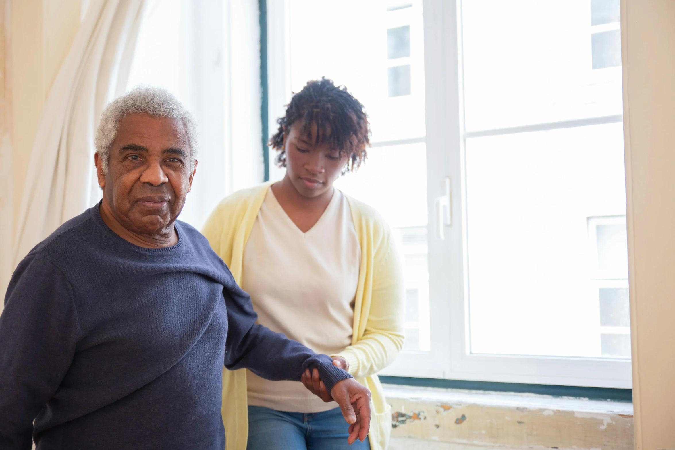 an older man and young woman standing by the window