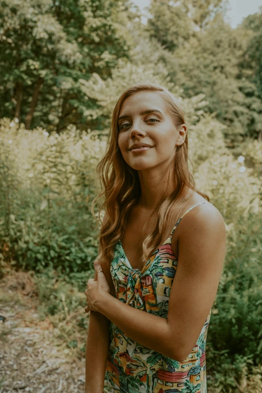 woman in floral dress leaning on bushy woods