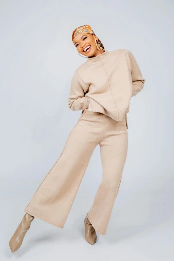 the model is wearing an off - white turtleneck sweater and wide legged pants