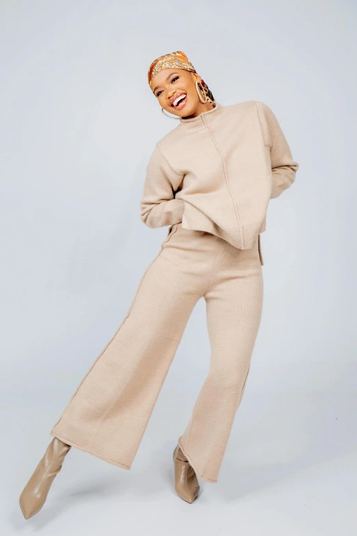 the model is wearing an off - white turtleneck sweater and wide legged pants