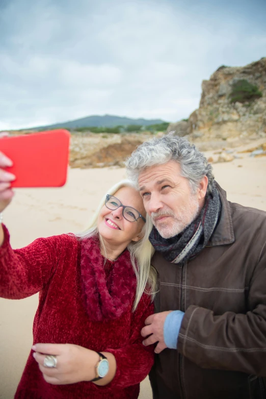 an older couple taking a selfie together on the beach