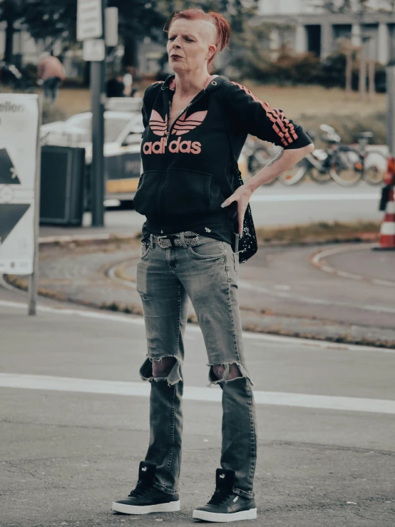 a woman standing on the street in ripped jeans
