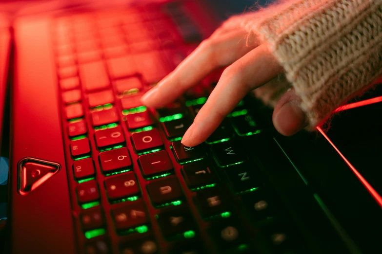 a person typing on a red lit laptop keyboard