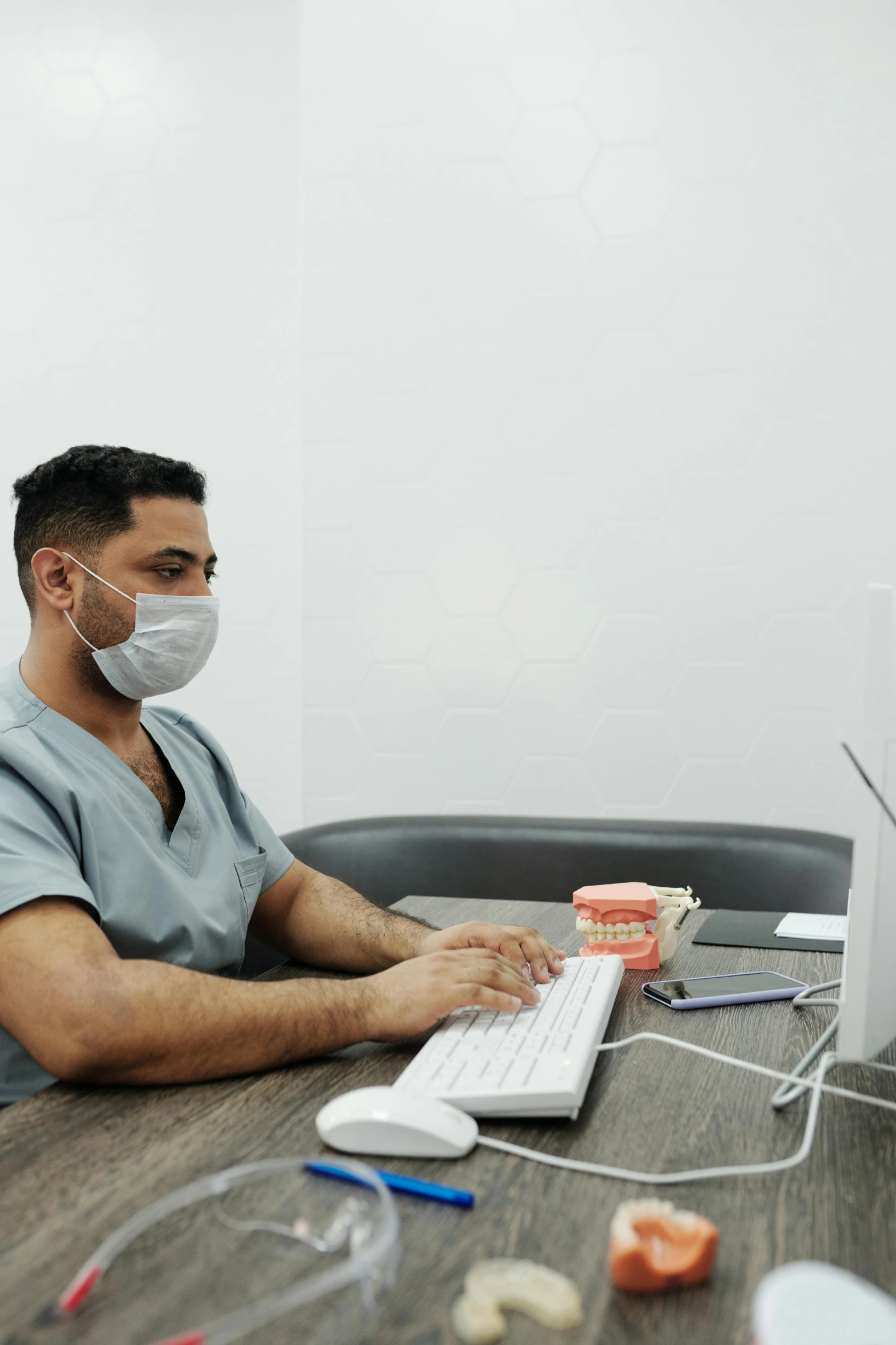 a man with a surgical mask sitting at a computer