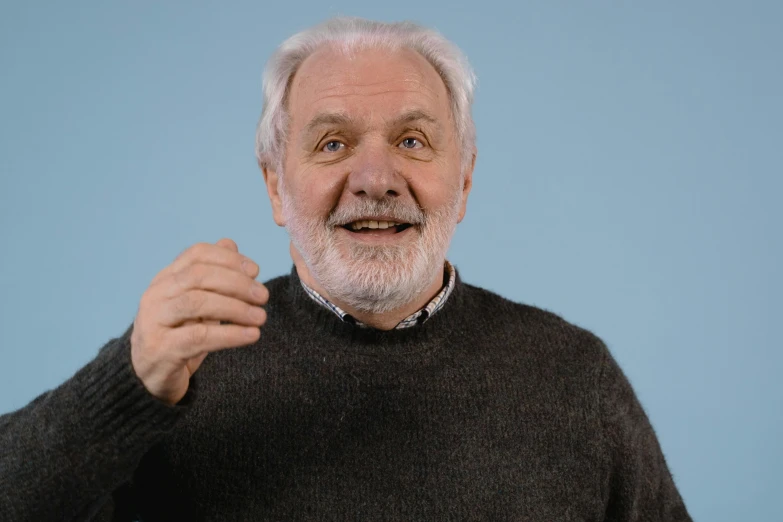 an elderly man poses with his hand to his face