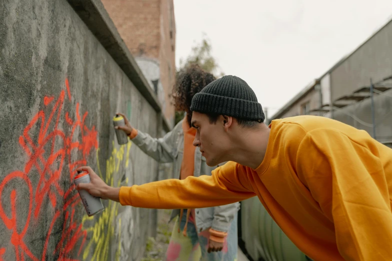 two men are writing on the concrete wall