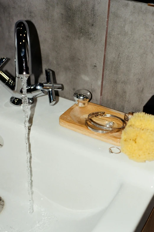 a sink with two gold rings and a soap brush on the sink