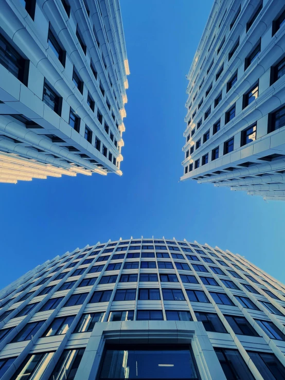 looking up at two skyscrs with blue sky in background