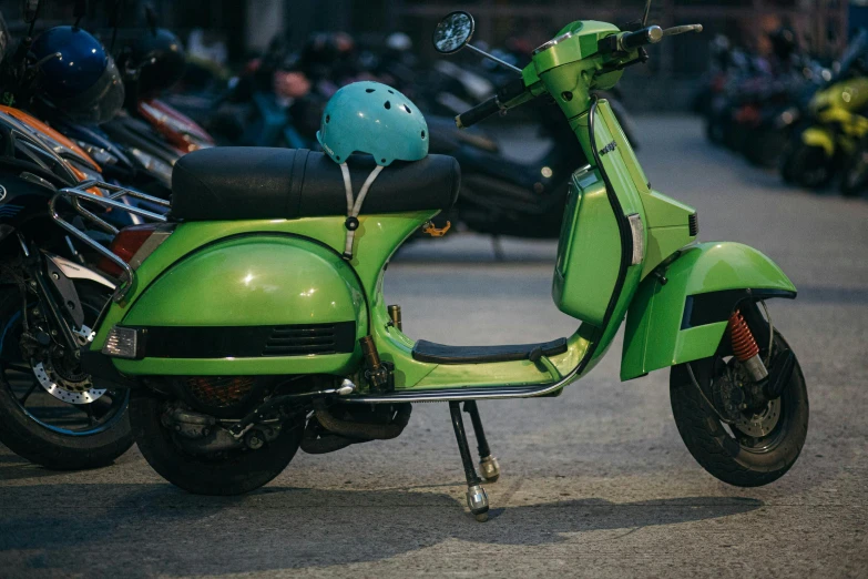 green motor scooter parked on street next to other motorcycles