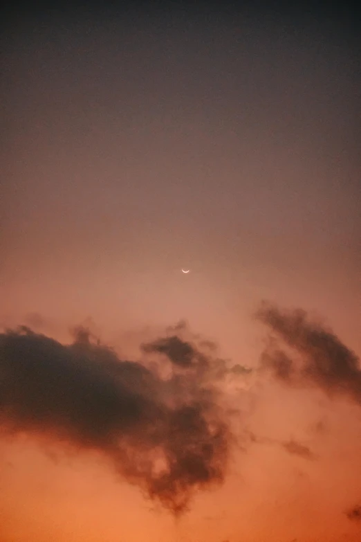 a sunset and plane flying by with a moon in the sky