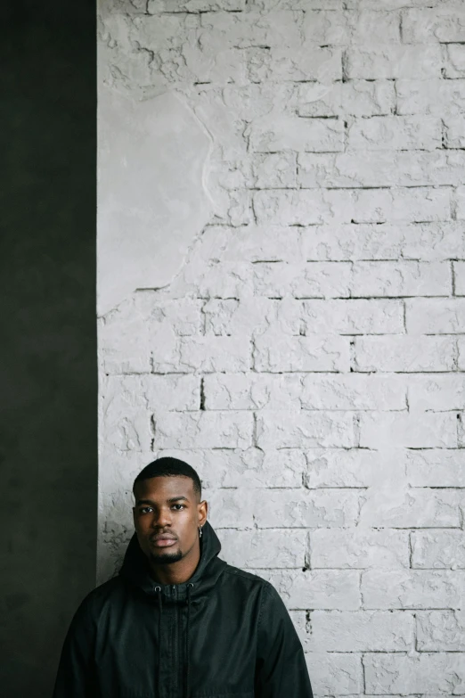 a man in black jacket leaning against wall